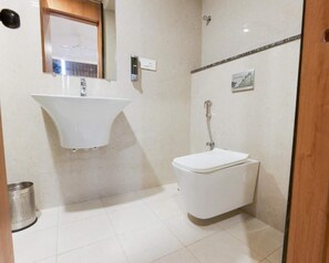 A bathroom with a white sink, a toilet, and a shower. - The Hoften Sterling Plaza Near BLR Airport (Bengaluru)