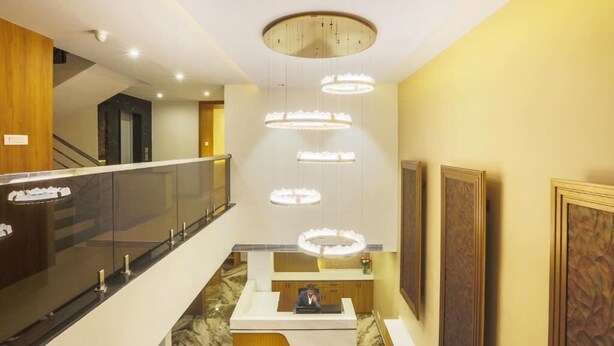 Un hall d’hôtel comprenant un comptoir d’accueil, un escalier et un lustre moderne.