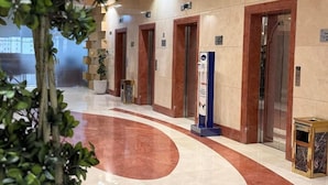 Een hotel lobby met marmeren vloeren, houten deuren en een receptiebalie.