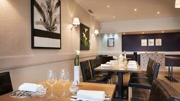 A dining area with a wooden table set for four, surrounded by black leather chairs.