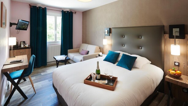 A hotel room with a bed, a desk, a chair, a TV, and a window with curtains. - Pont Du Chalon Hôtel And Restaurant (Marges)