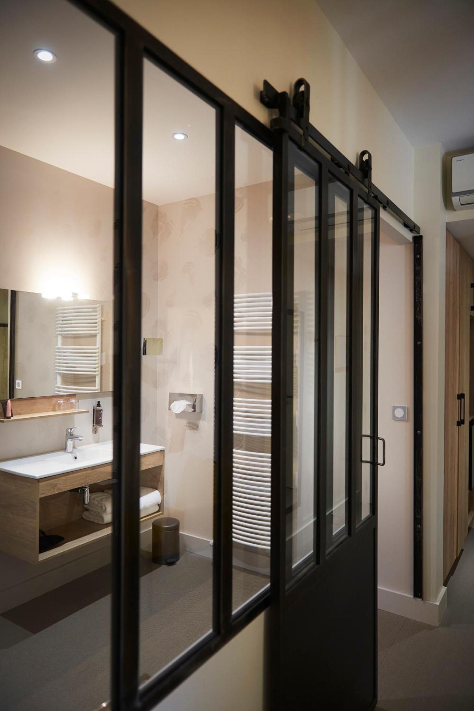 A modern bathroom with a glass partition, a sink, a mirror, and a towel rack.