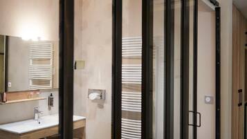 A modern bathroom with a glass partition, a sink, a mirror, and a towel rack.