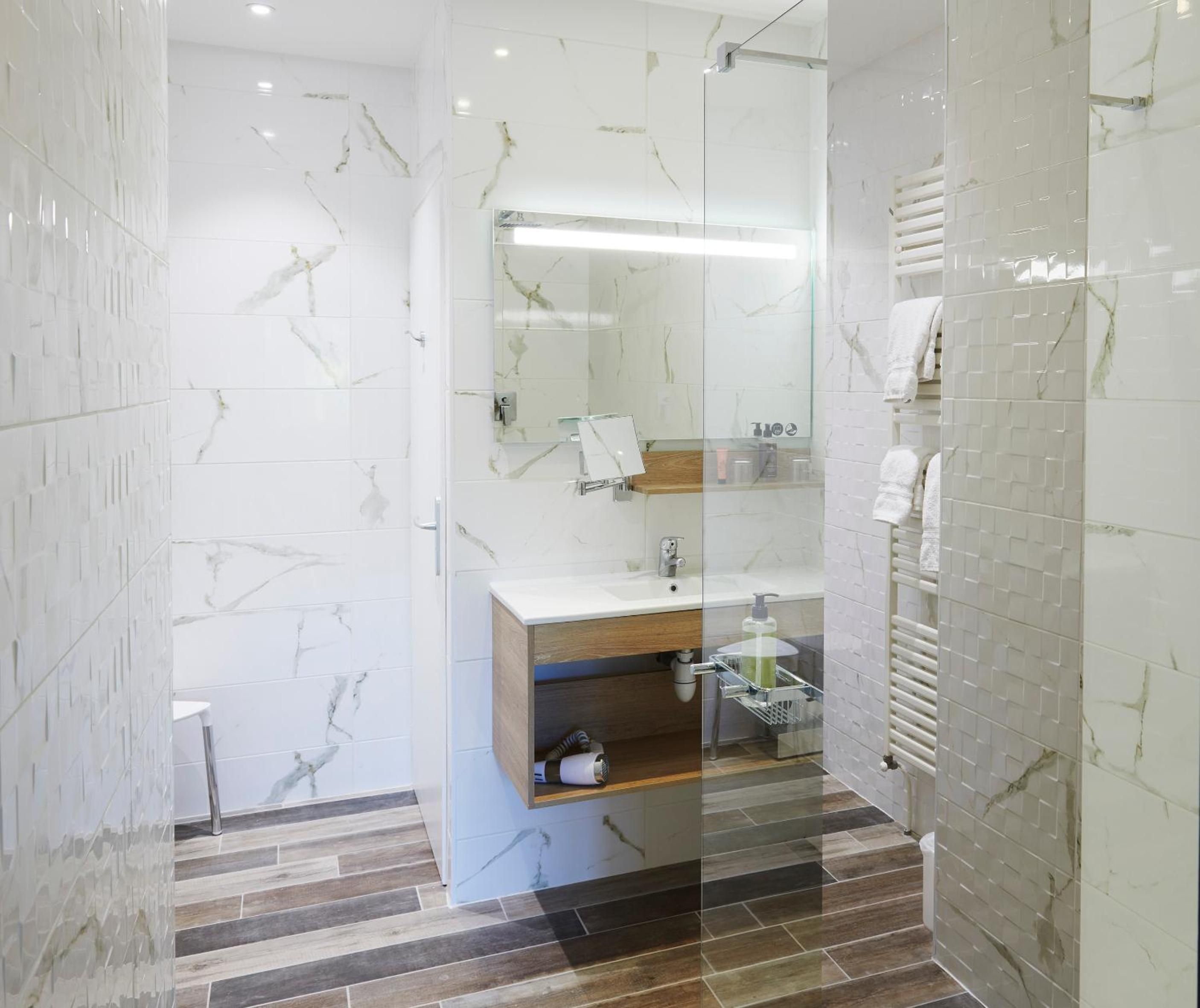 A modern bathroom with a glass-enclosed shower, a vanity with a mirror, and a towel rack.