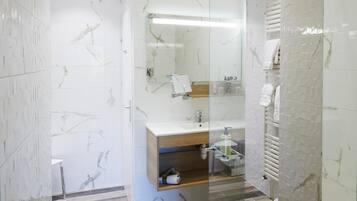 A modern bathroom with a glass-enclosed shower, a vanity with a mirror, and a towel rack.
