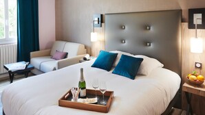 A hotel room with a large bed, two bedside tables, a sofa, and a window with curtains. - Pont Du Chalon Hôtel And Restaurant (Marges)