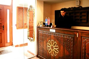 A reception desk with a nameplate, a telephone, and flags. - Isa Begov Hamam Hotel (Sarajevo)