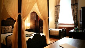 A four-poster canopy bed with a wooden headboard, a bedside table with a lamp, and a window with curtains. - Isa Begov Hamam Hotel (Sarajevo)