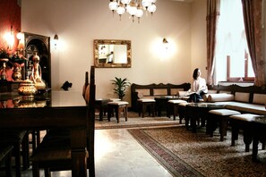 A traditional living room with a sofa, chairs, a dining table, and a chandelier. - Isa Begov Hamam Hotel (Sarajevo)