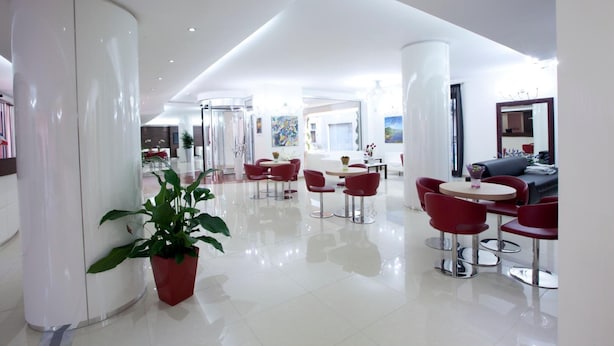 Eine moderne Hotelhalle mit einer zentralen Sitzgruppe, einem Empfangsbereich und einer großen Pflanze.