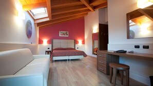 Ein Schlafzimmer mit Bett, Schreibtisch, Stuhl, Spiegel und einem Oberlicht.