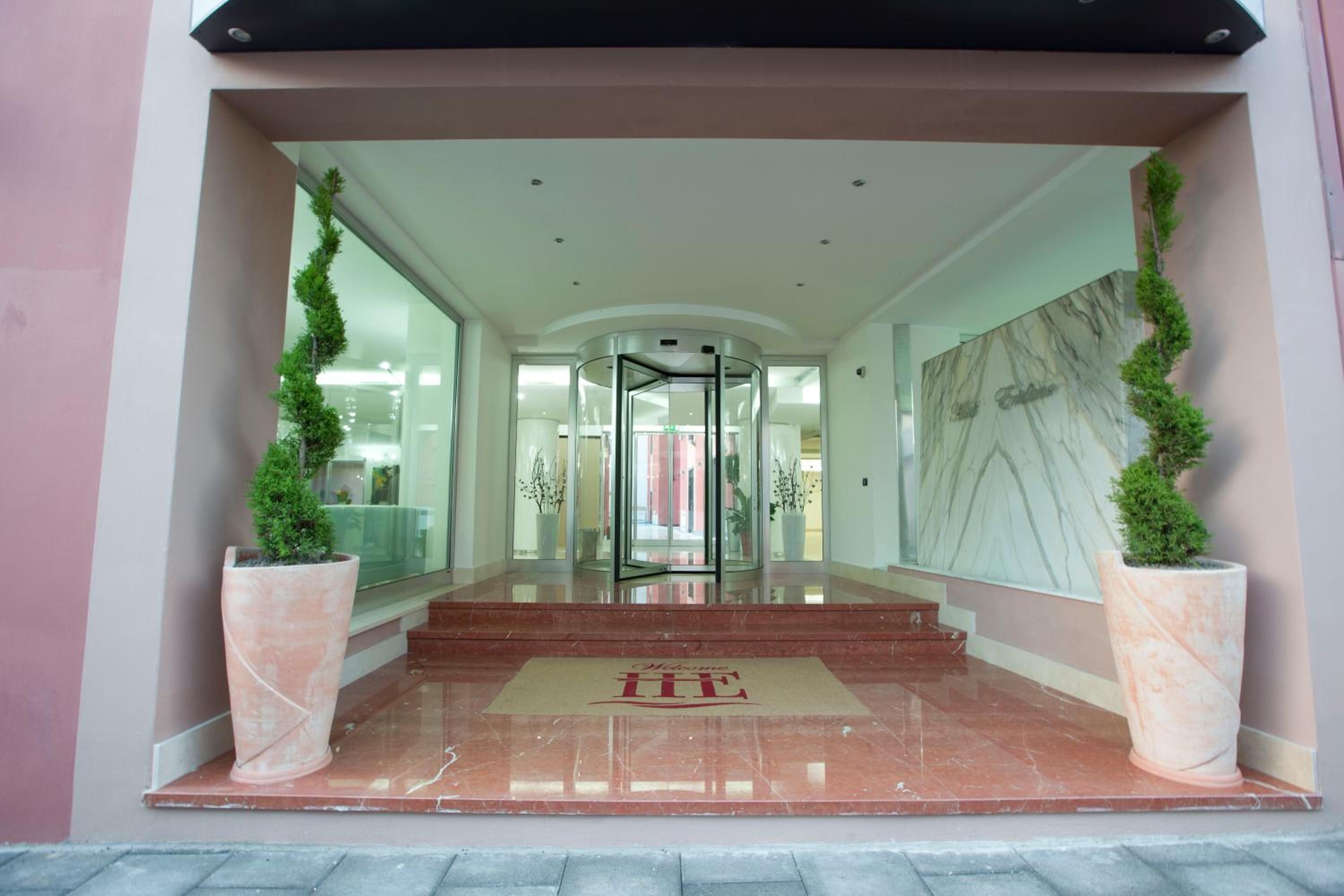 A hotel entrance with a revolving door, a marble floor, and potted plants.