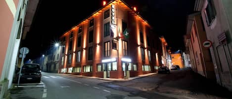 A hotel with a corner location, multiple floors, and illuminated signage.
