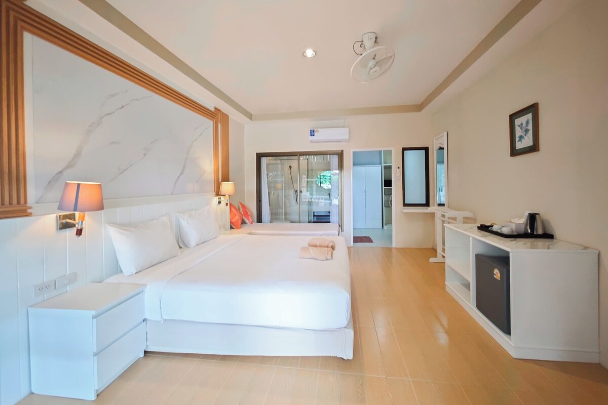 Habitación de hotel con una cama grande, mesitas de noche, un escritorio con silla, un espejo y un armario.