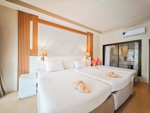 Ein Hotelzimmer mit zwei Betten, einem Kopfstück mit Marmor-Muster, einem weißen Nachttisch und einer Glastür, die auf einen Balkon führt.