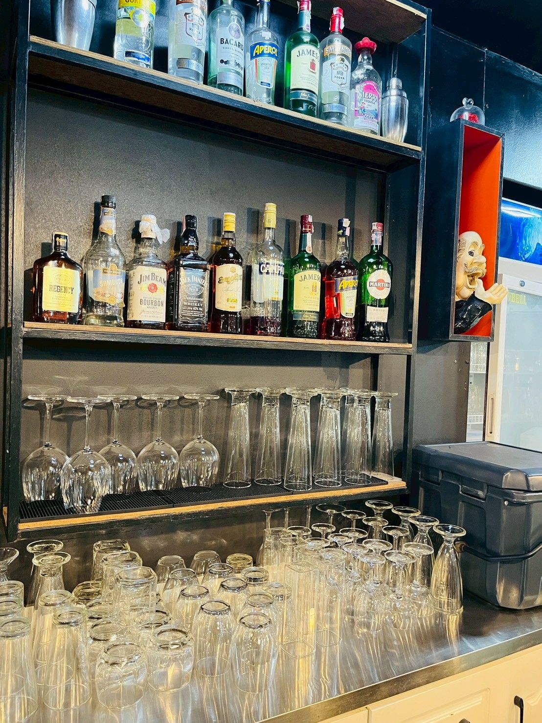A bar area with shelves of liquor bottles and a variety of glasses.