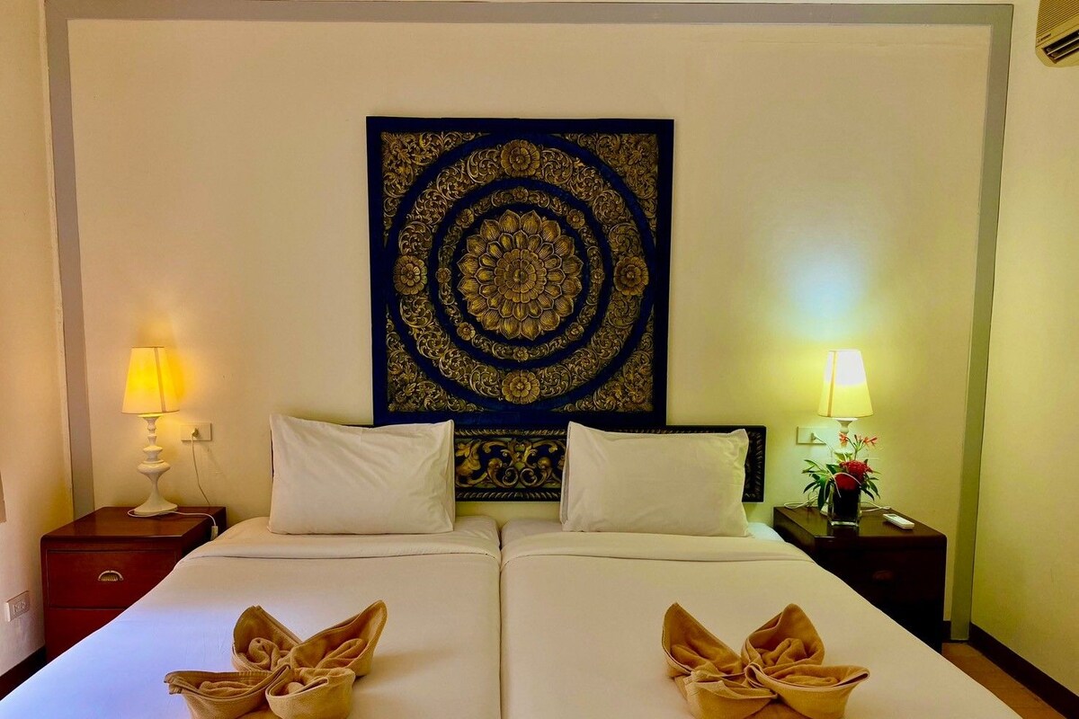 Une chambre d’hôtel avec un grand lit, deux oreillers, une tapisserie et deux lampes de chevet.
