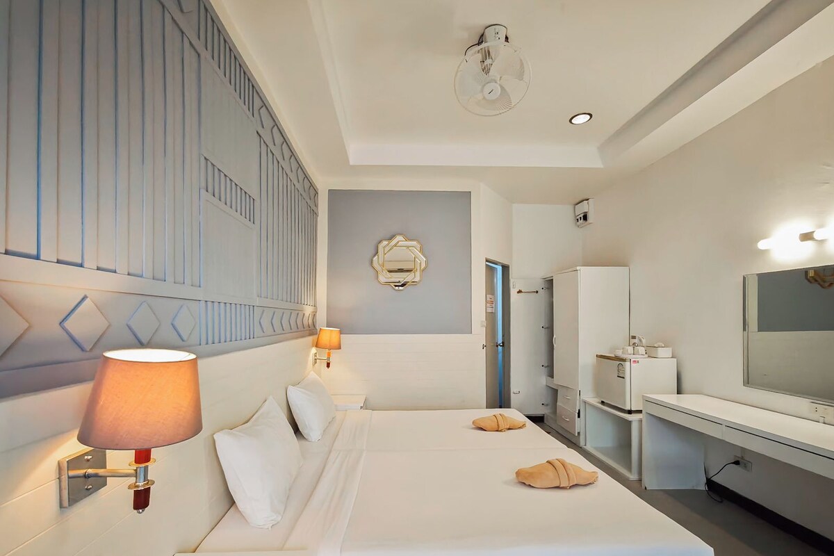 Une chambre d’hôtel équipée d’un lit, d’une lampe de chevet, d’un miroir fixé au mur et d’un téléviseur.