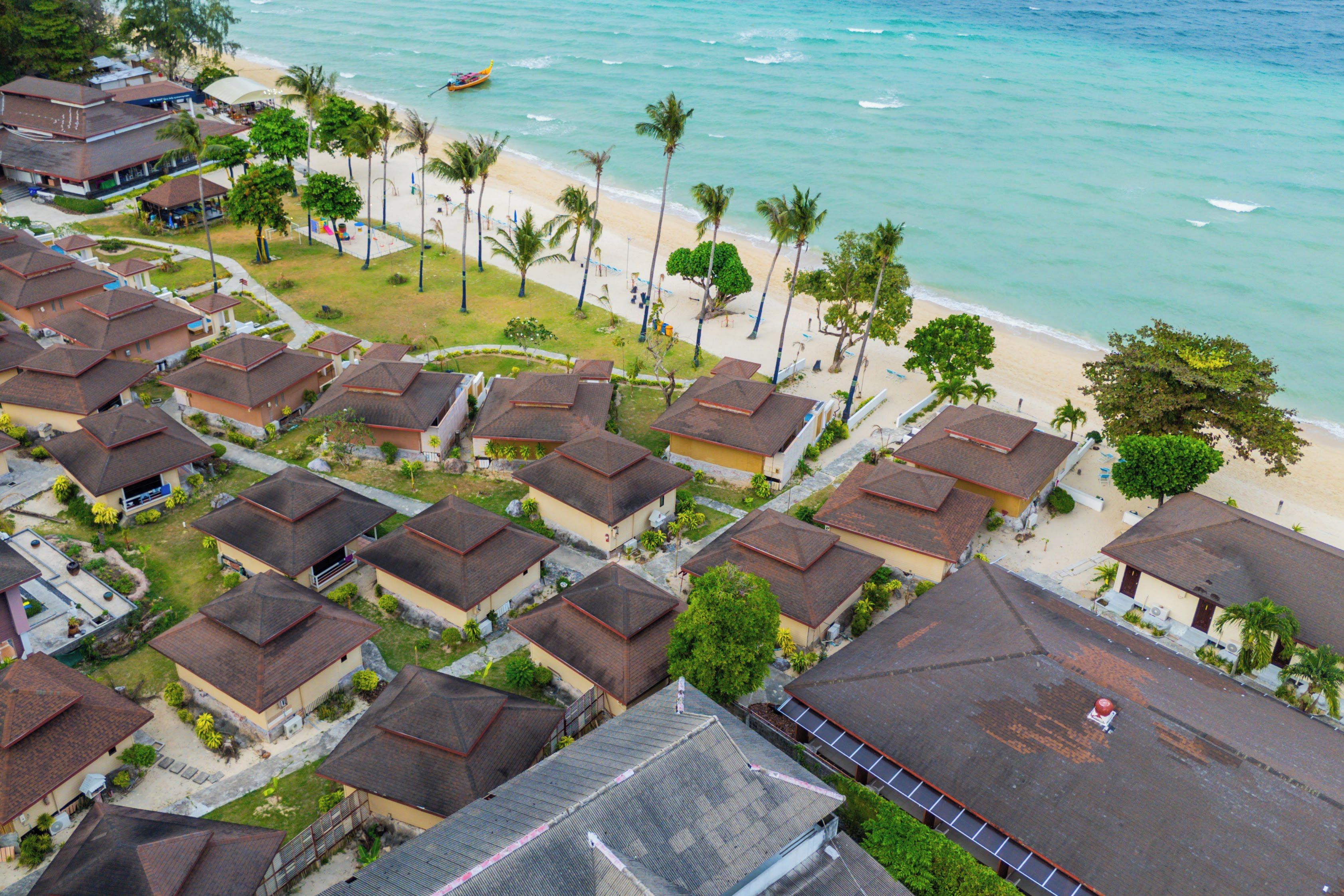 A residential area with multiple houses, a beach, and a boat on the water.