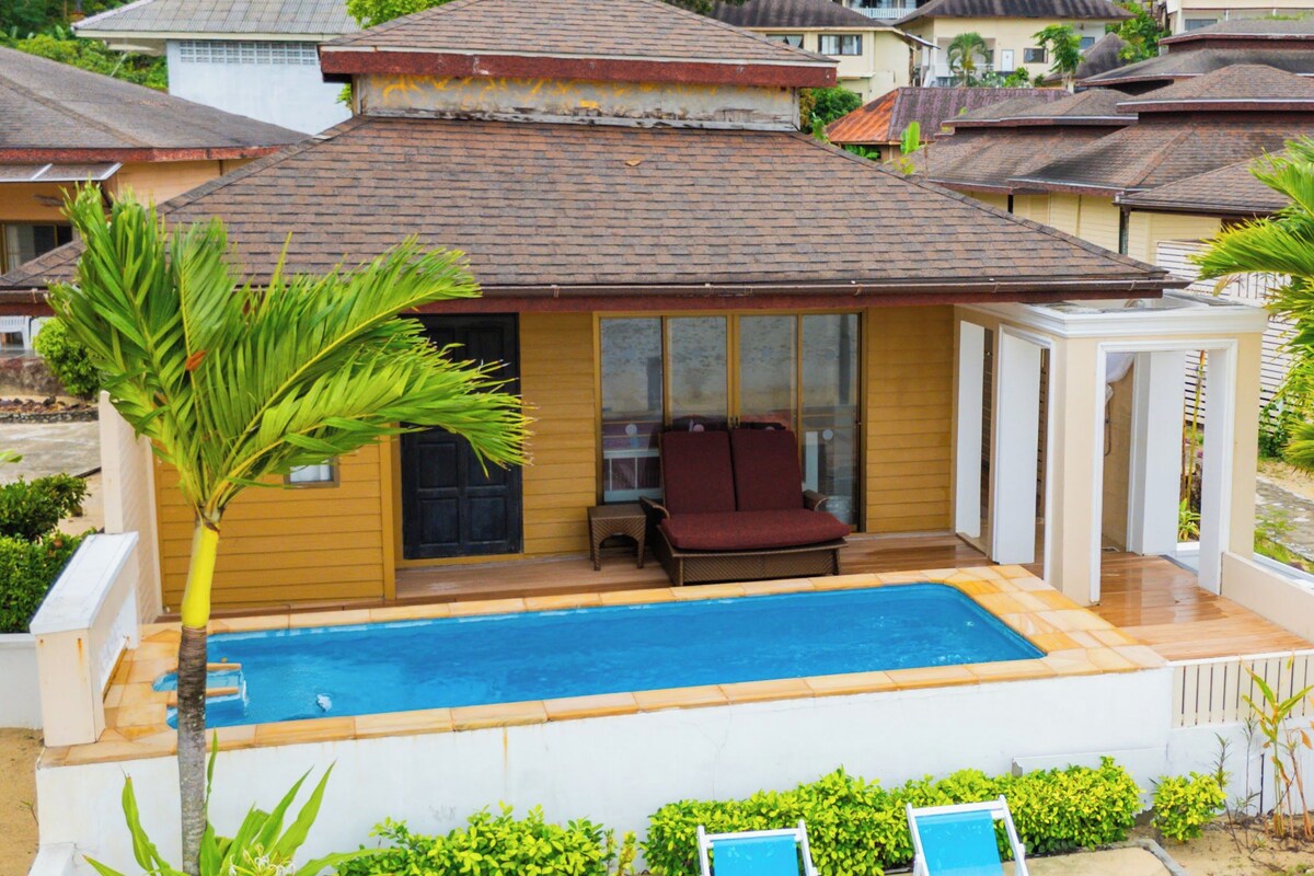 Propiedad residencial con piscina, dos sillones de descanso y un porche cubierto.