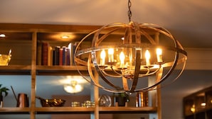 A chandelier with multiple lights, a wooden bookshelf in the background, and a variety of decorative items on shelves. - The Bear (Bath)