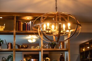 A chandelier with multiple lights, a wooden bookshelf in the background, and a variety of decorative items on shelves. - The Bear (Bath)