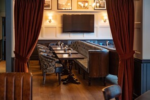 A restaurant with a long wooden bench seating area, tables, and chairs. - The Bear (Bath)
