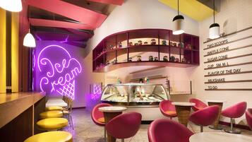 A dessert shop interior with neon signage, shelves of colorful candies, and seating areas.