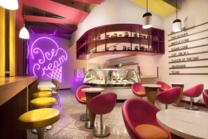 A dessert shop interior with neon signage, shelves of colorful candies, and seating areas. - Lopesan Caoba Lagoon Resort, Spa & Casino (Punta Cana)
