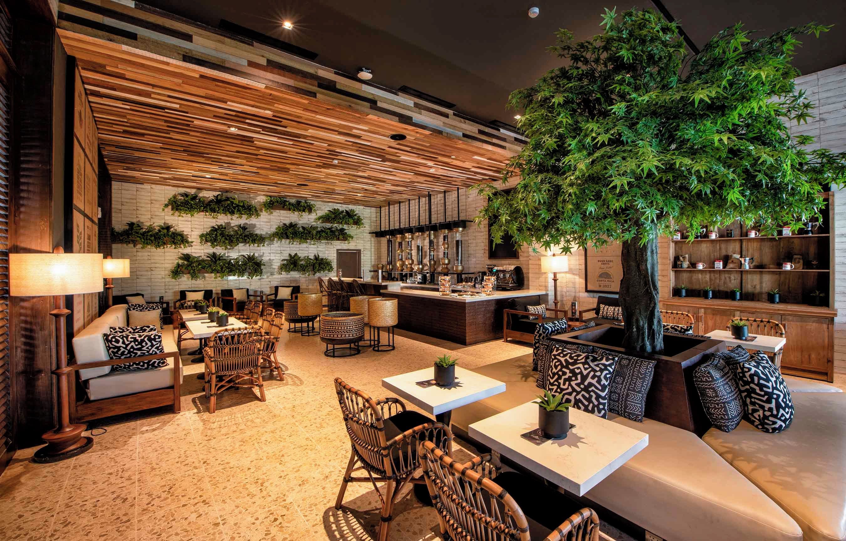 Un área de descanso moderna con asientos, un bar y un árbol artificial grande.