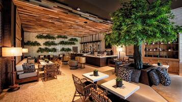 Ein stilvoller Lounge-Bereich mit Sitzgelegenheiten, einer Bar und einem großen Kunstbaum.