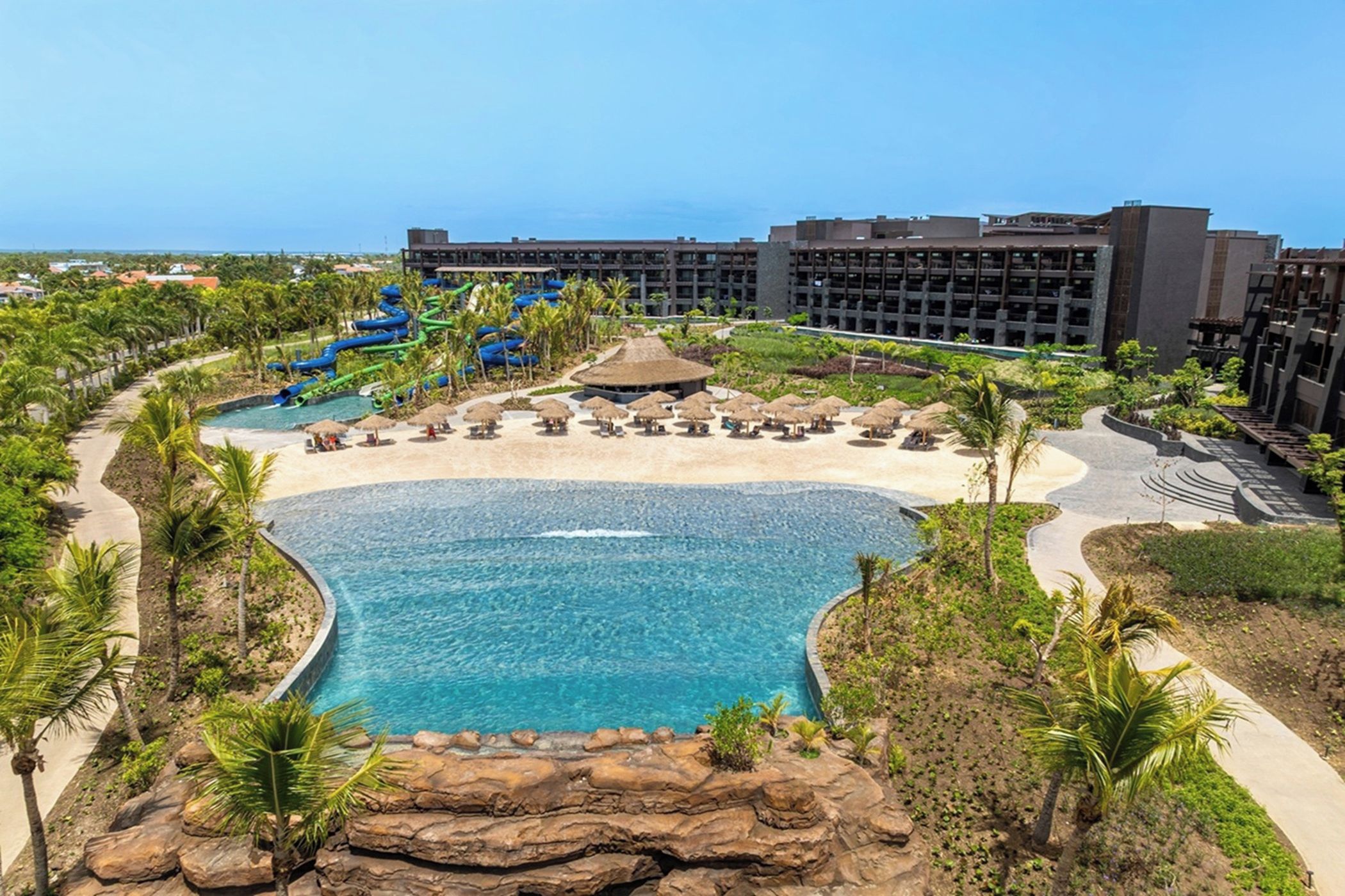 A resort with a central pool, palm trees, and a water park.