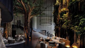 A modern interior with a central staircase, seating areas, and a wall with artificial greenery.