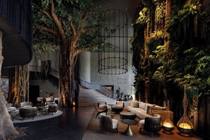 A modern interior with a central staircase, seating areas, and a wall with artificial greenery. - Lopesan Caoba Lagoon Resort, Spa & Casino (Punta Cana)