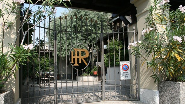 Ein begrenzter Zugang mit einem Metalltor, einem Verbotsschild für Parkverbietung und einem Gebäude mit dem 'HR'-Logo.