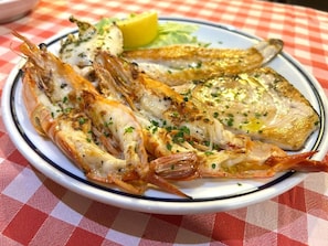 Un piatto di pesce alla griglia con spicchi di limone e una tovaglia a quadri.