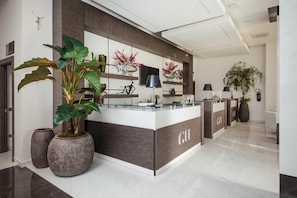 A reception area with a reception desk, potted plants, and a modern interior design. - Grieco Business & Spa Hotel (Cerignola)