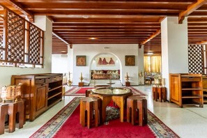 A traditional room with a central wooden table, red carpet, and wooden furniture. - Hotel Le Grand Imilchil (Marrakech)