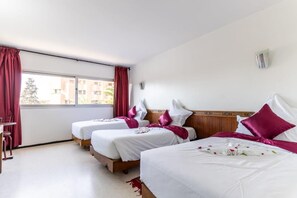 A hotel room with two beds, a window with curtains, a wooden headboard, and a small table. - Hotel Le Grand Imilchil (Marrakech)