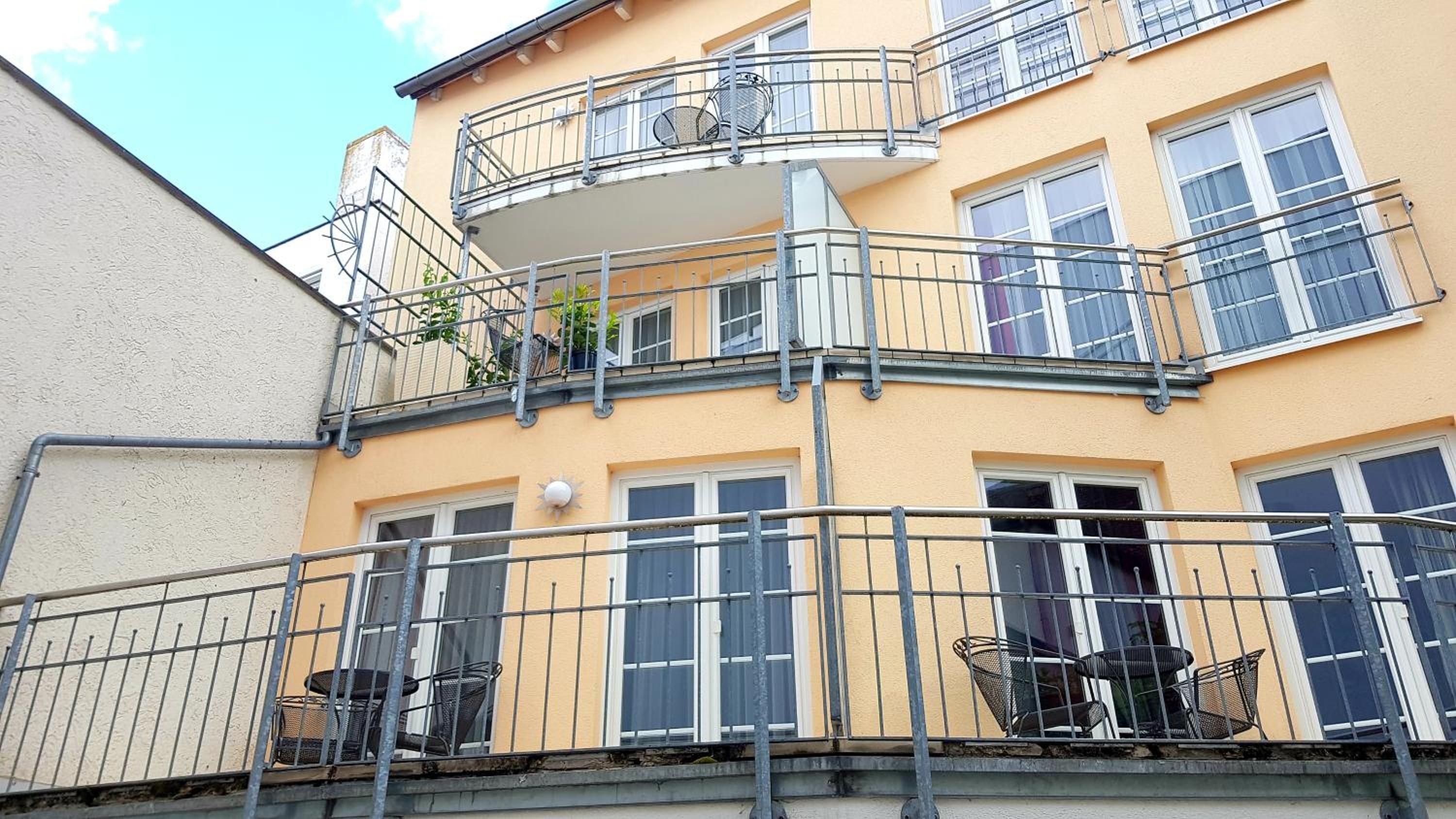 Ein mehrstöckiges Gebäude mit Balkonen, Geländern und Fenstern.