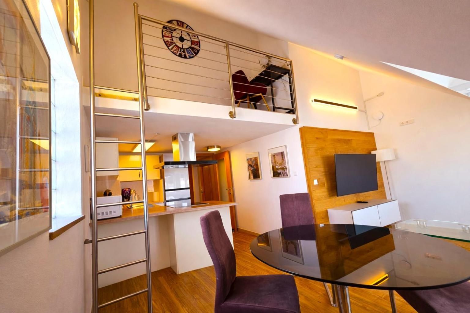 Eine moderne Wohnung mit Essbereich, Küche und Schlafgalerie mit Balkon.