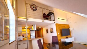 Eine moderne Wohnung mit Essbereich, Küche und Schlafgalerie mit Balkon.