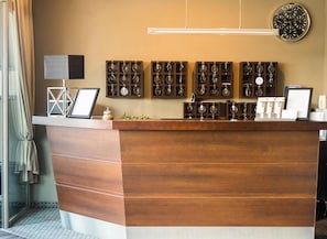 A reception desk with a wooden finish, a wall-mounted clock, and a series of keychains on display. - Comm Hotel Poznan Airport (Poznań)