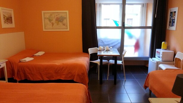 A hotel room with two beds, a small table with chairs, a window, and a television. - Affittacamere Andronaco (Milan)