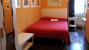 A hotel room with a bed, a desk, a chair, and a window with curtains. - Affittacamere Andronaco (Milan)