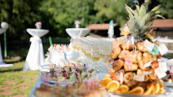 An outdoor buffet with various food items and drinks, including a pineapple centerpiece.