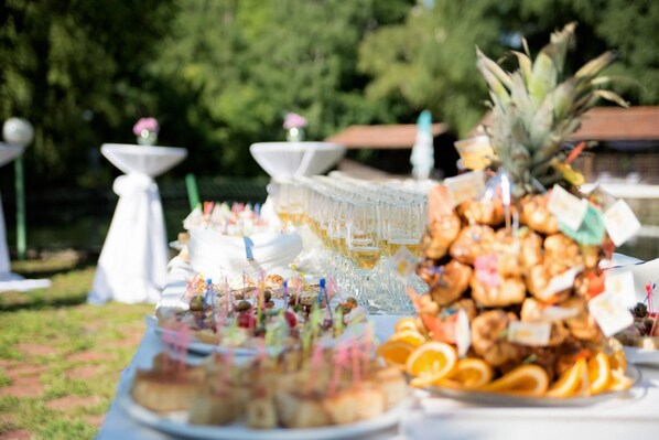 An outdoor buffet with various food items and drinks, including a pineapple centerpiece.