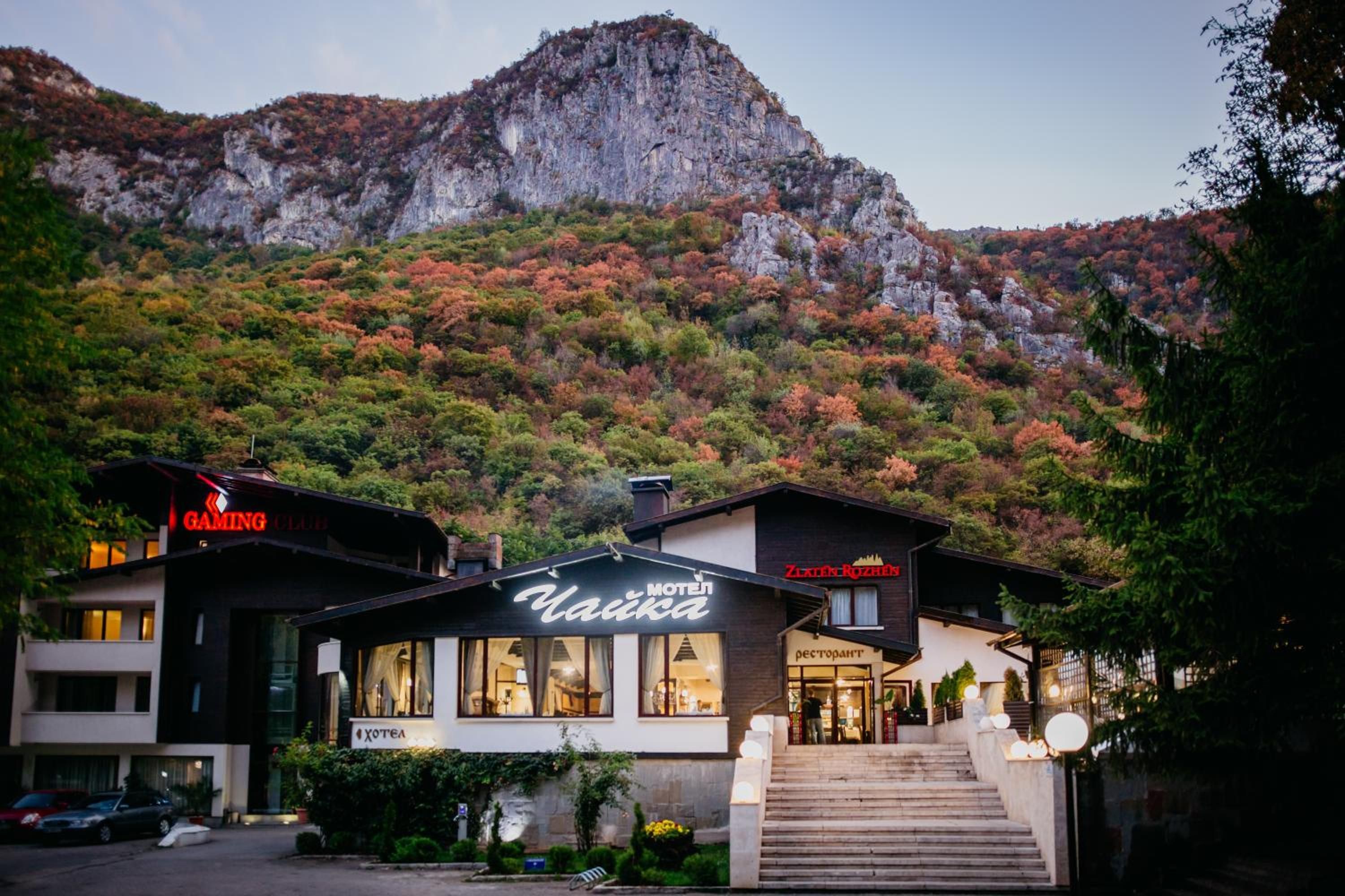 A hotel with a mountain backdrop, featuring a restaurant and a gaming club.