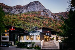 A hotel with a mountain backdrop, featuring a restaurant and a gaming club.