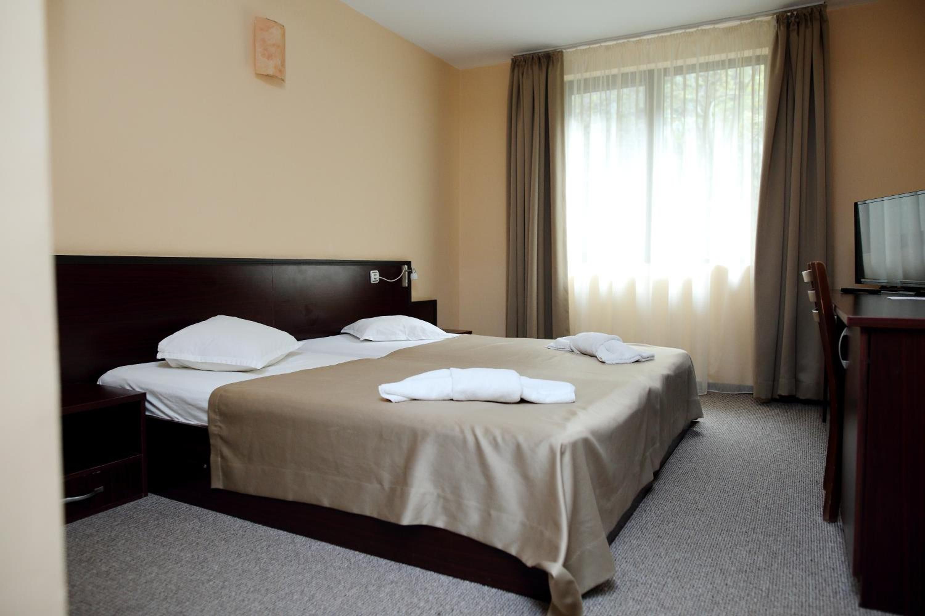 A hotel room with a double bed, a TV, and a desk.